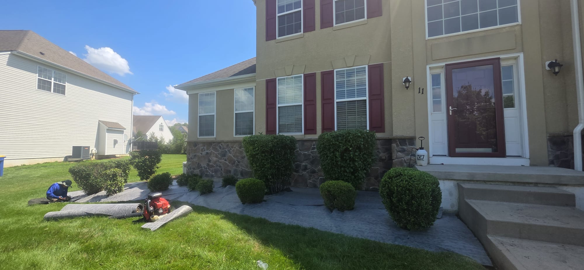 Crew installing landscape fabric in freshly weeded and edged front beds in Hillsborough, NJ